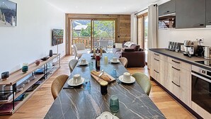 A modern kitchen with a marble countertop, wooden cabinets, and a dining area with a long table and chairs. - Tamaris - Morzine - secteur Planet (Morzine)