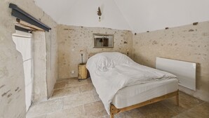 A bedroom with a wooden bed, a small bedside table, a mirror, and a radiator. - Old farmhouse renovated for 6 into 2 flats (Fossemagne)