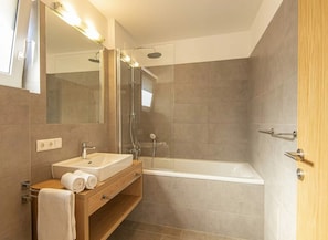 A modern bathroom with a large bathtub, a vanity with a sink, and a mirror.
