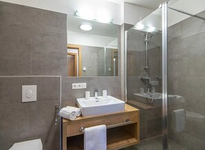 A modern bathroom with a glass-enclosed shower, a wooden vanity with a sink, and a mirror above the vanity. - Apartment in Wagrain Near Grafenberg Lift (Wagrain)