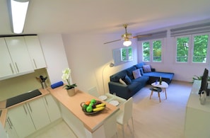 A modern living space with a kitchen, dining area, and a blue sofa.