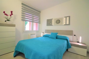 A bedroom with a bed, bedside table, and a wall-mounted artwork.
