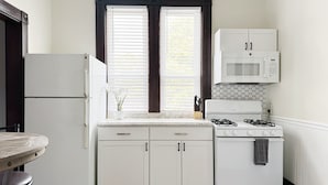 A compact kitchen with white cabinets, a built-in microwave, a gas stove, and a refrigerator.