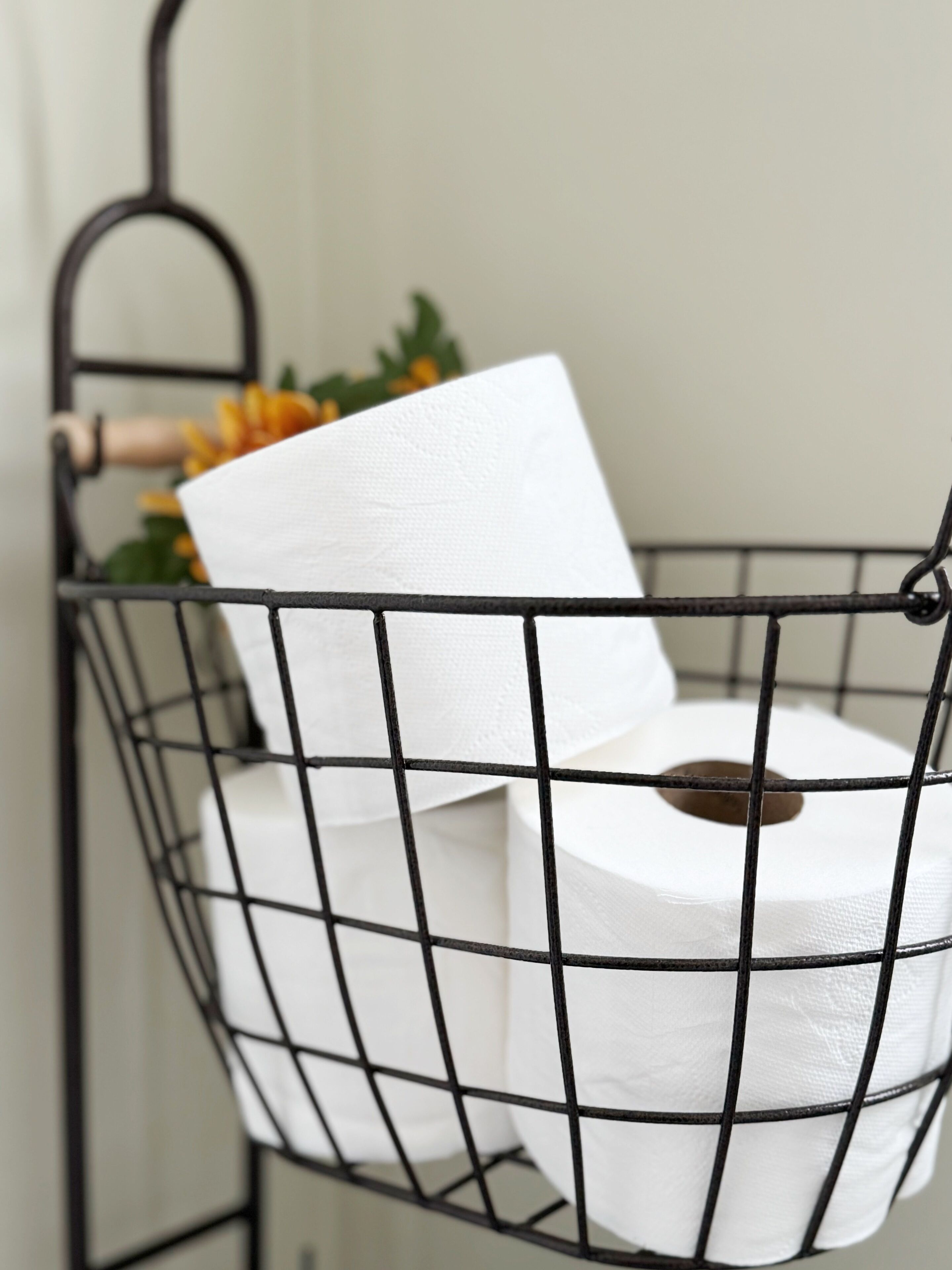 Un panier en fil de métal contenant des rouleaux de papier toilette.