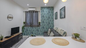 Ein modernes Schlafzimmer mit Bett, Fernseher, Schreibtisch und einem Fenster mit Vorhängen.