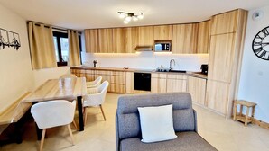 Una cucina moderna con mobili in legno, un'area pranzo con tavolo e sedie, e un soggiorno con divano.