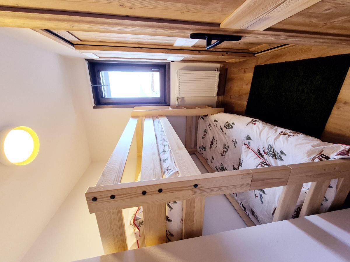 A small, cozy room with a bunk bed, a skylight, and a wall-mounted heater.