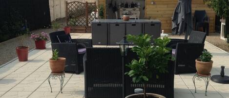 An outdoor patio with a seating area, a large potted plant, and a wooden fence.