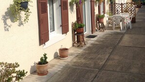 Een rij huizen met luiken, planten in potten en tuinmeubilair.