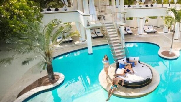 Ein Swimmingpool mit einem runden Whirlpool, Liegestühlen und Palmen.