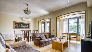 A spacious living room with a brown leather sofa, a wooden coffee table, and a dining area with a table and chairs. - Apartment in Roses by the Beach (Roses)