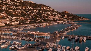 A coastal town with a marina filled with boats, surrounded by densely packed buildings on a hillside. - Apartment in Roses by the Beach (Roses)