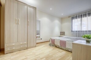 A bedroom with a bed, a wardrobe, a chair, and a window with curtains. - Apartment in Roses by the Beach (Roses)