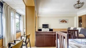 A modern living room with a sofa, chairs, a TV, and a dining area. - Apartment in Roses by the Beach (Roses)