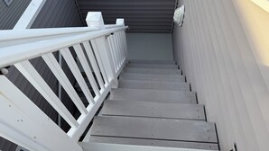 A staircase with white railings and gray steps leading to a covered area.