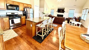 A spacious kitchen with wooden cabinets, a built-in oven, and a refrigerator. There is a dining area with a wooden table and chairs.