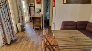 Ein gemütlicher Wohnraum mit Esstisch aus Holz, einer Couch, einer Küchenzeile und einem kleinen Badezimmer.