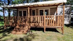 Eine Holzterrasse mit überdachter Veranda, einer Treppe und einem kleinen Fenster.