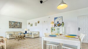A living room with a dining area, featuring a sofa set, a coffee table, and a dining table with chairs. - Apartment in Roses Near Canyelles Beach (Roses)
