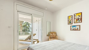A bedroom with a bed, a chair, and a sliding door leading to a balcony. There are three framed artworks on the wall. - Apartment in Roses Near Canyelles Beach (Roses)