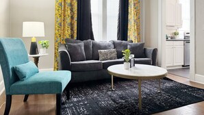 Un salon avec un canapé gris, un fauteuil turquoise et une table basse ronde.