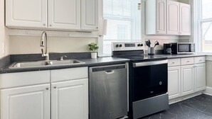 Une cuisine moderne avec des meubles blancs, des appareils en acier inoxydable, un lave-vaisselle et un four à micro-ondes.