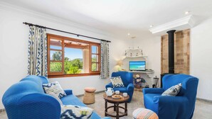 A living room with blue sofas, a small round table, and a fireplace. - Can Pansa - Three Bedroom Villa, Sleeps 6 (Pollensa)