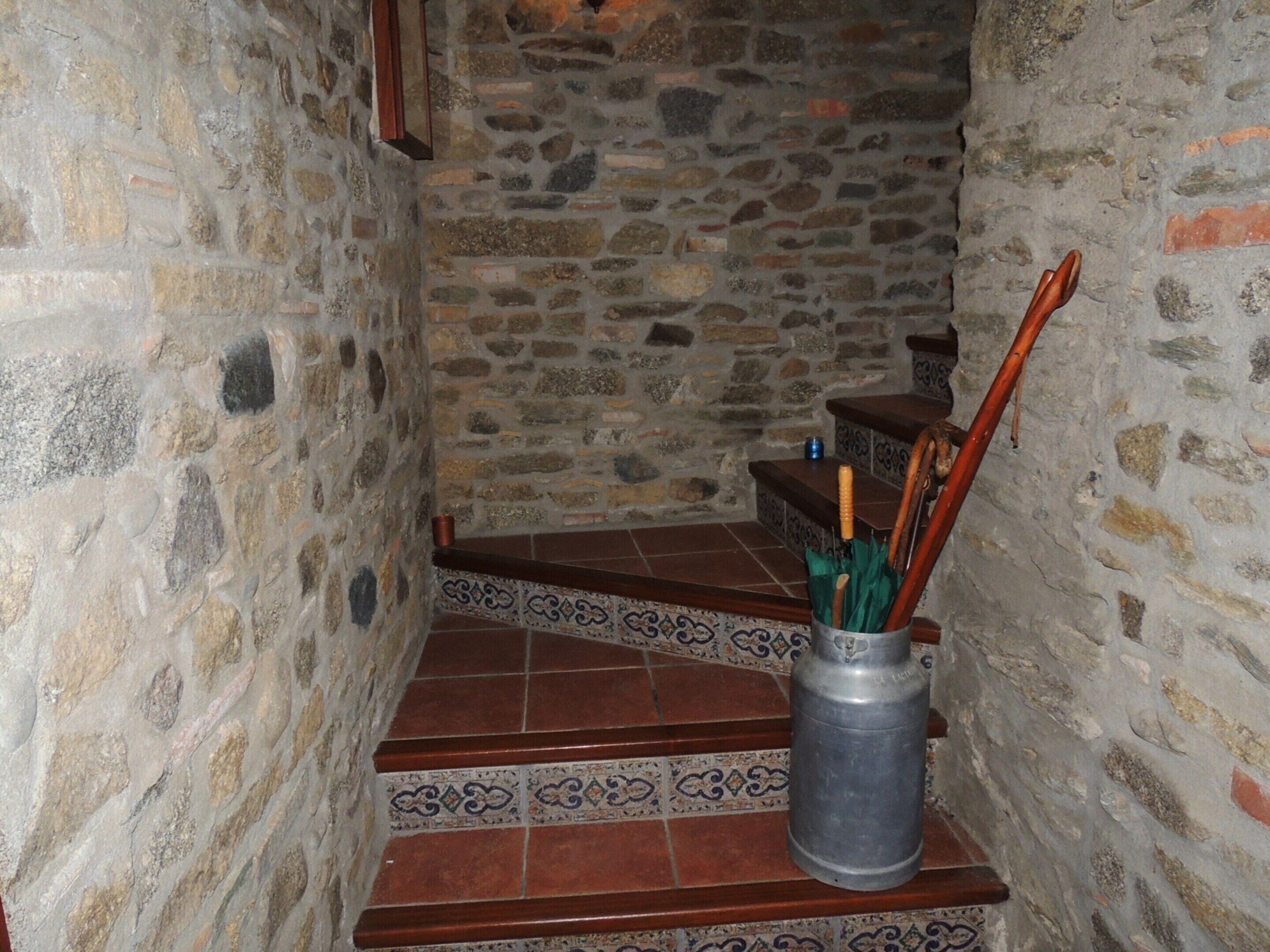 A stone staircase with patterned tiles and a metal bucket with utensils.