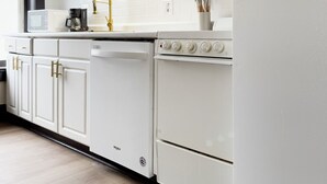 Une cuisine moderne avec des meubles blancs, un four encastré et un lave-vaisselle.