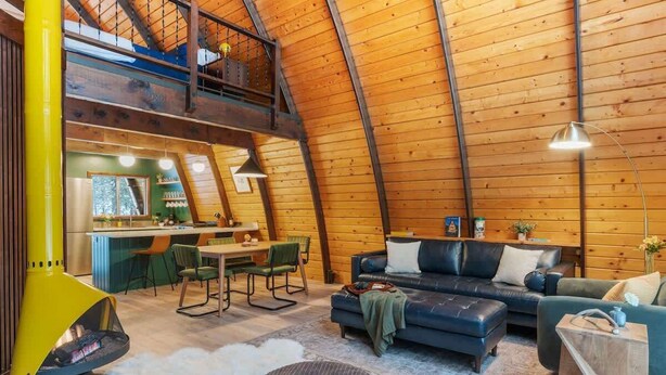 A cozy, high-ceilinged wooden interior with a dining area, a sofa, and a fireplace. - Retro A-Frame w/ Hot Tub, Perfect Couple's Getaway (Island Park)