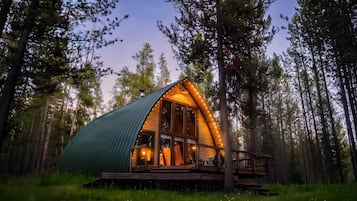 A cabin with a sloped roof, large windows, and a wooden deck.
