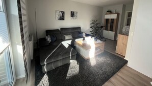 Una sala de estar moderna con un sofá, una mesa de centro y una obra de arte en la pared.