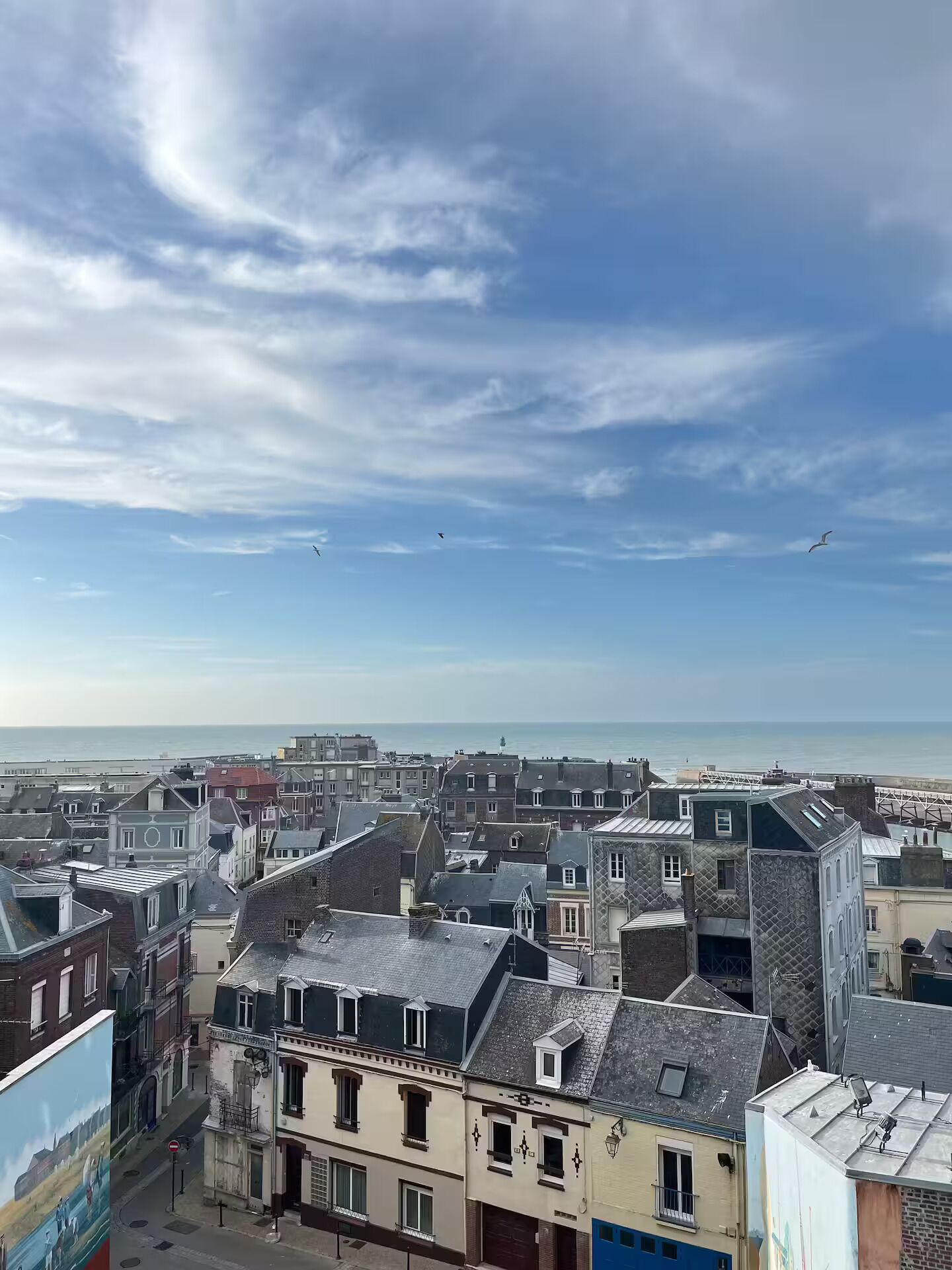 Un poble costaner amb edificis històrics, un cel serè i vista al mar.