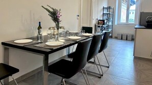 A dining area with a long table set for four, black chairs, and a small plant on the table. - Beautiful house in the heart of Rome 20meters from Piazza Venezia/Trevi Fountain (Roma)