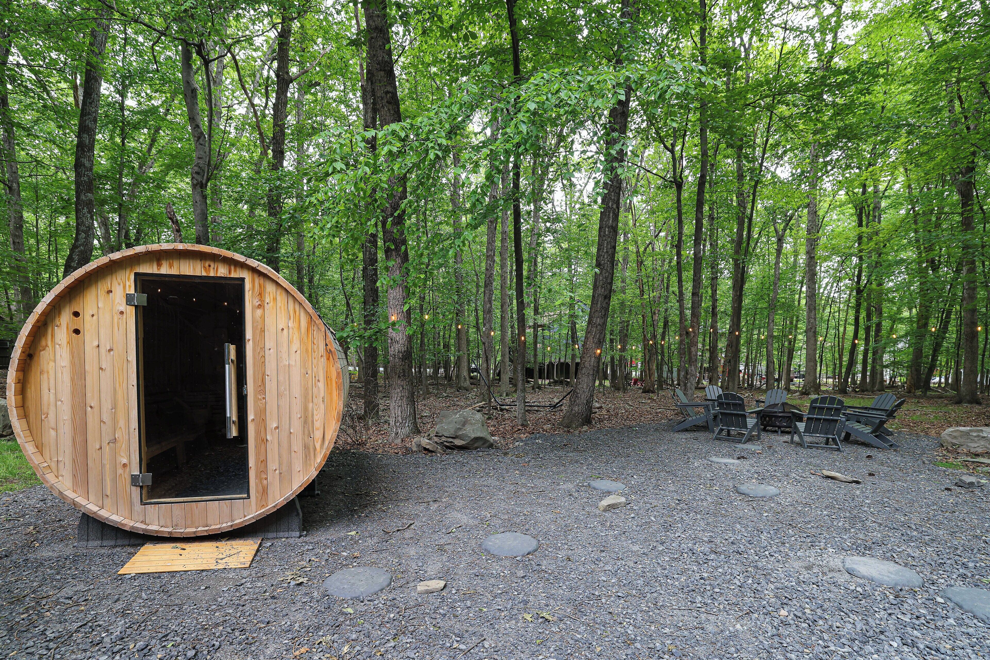 A wooden cabin with an open door, surrounded by a forest.