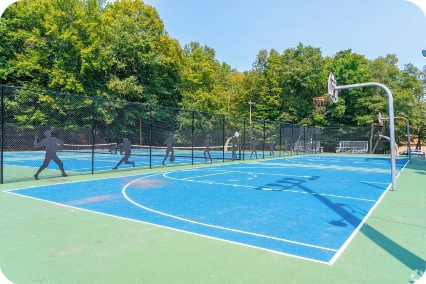 Un terrain de basket-ball en plein air, équipé d’un filet, d’un panier et d’une clôture.