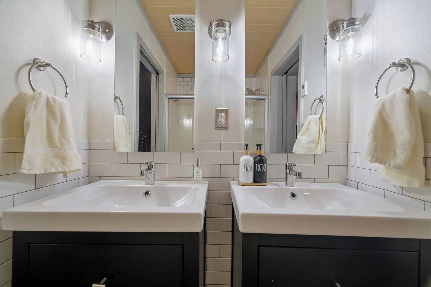 A bathroom with two sinks, a mirror, and a towel rack.
