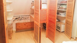 Un dressing accessible sans porte, doté d’étagères ouvertes, d’un étendoir et d’un petit espace de rangement.