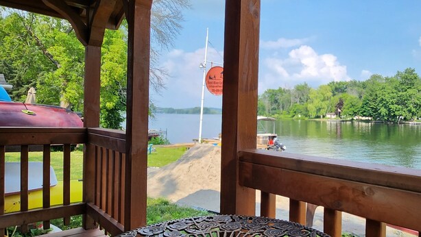 Una terraza de madera con vistas a un lago, con un letrero que dice Trent River Cottage and Boat Camp.