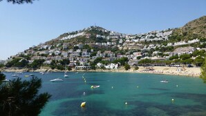 A coastal town with buildings on a hillside, a beach, and boats in the water. - Modern Flat by the Sea (Castello d'Empuries)