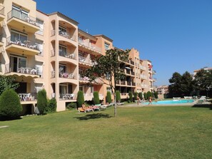 A multi-story hotel with balconies, a swimming pool, and a well-maintained lawn. - Modern Flat by the Sea (Castello d'Empuries)