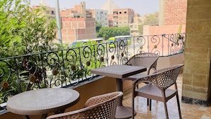 A balcony with a tiled floor, metal railing, and wicker furniture. - Kemt pyrimds view  (Giza)
