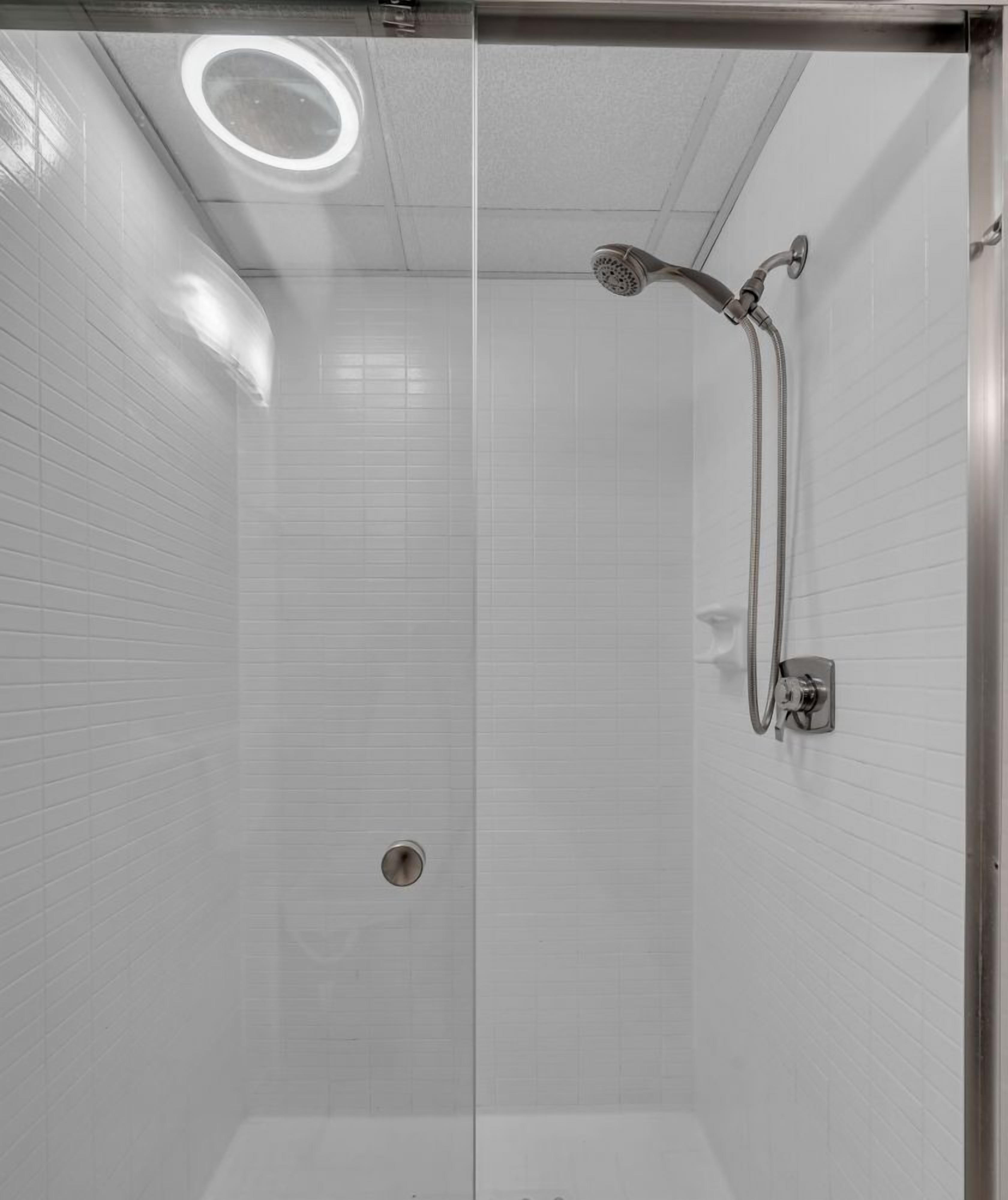 Una ducha moderna con cabezal de ducha manual y grifo empotrado en la pared.