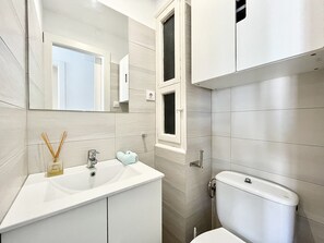 A modern bathroom with a white sink, mirror, and toilet.