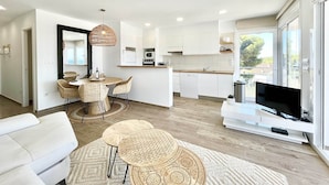 A modern apartment with a dining area, kitchen, living room, and a balcony with a TV. - Apartment Near Canyelles Petites Beach (Roses)