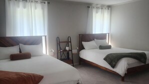 Ein Hotelzimmer mit zwei Einzelbetten, einem Holzkopfstück, einem kleinen Tisch und einem Stuhl.