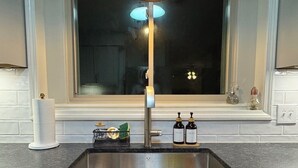 Eine Küche mit einer Granitabdeckung, einer Edelstahlspüle und einem Fenster darüber.