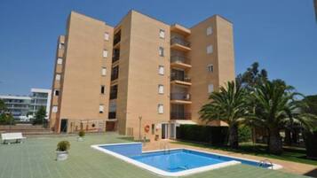 Un edificio de varios pisos con una piscina delantera.