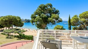 A terrace with a view of a beach and the sea, featuring a table and chairs. - Apartment in Roses Near Beach (Roses)