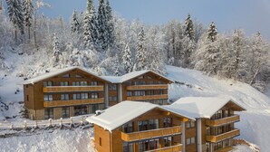 A wooden lodge with multiple balconies and a snow-covered landscape. - Chalet in Wagrain Near the Flying Mozart (Wagrain)